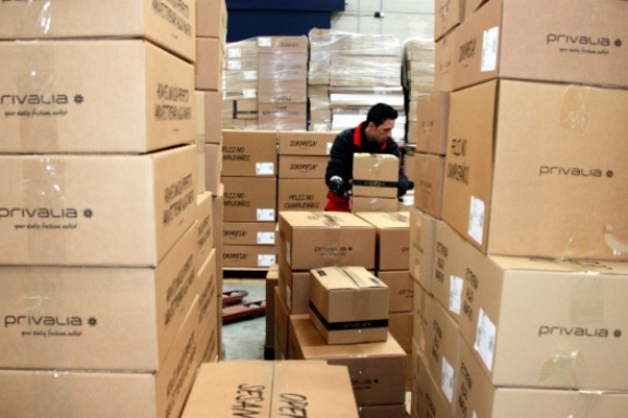 Un empleat envoltat de piles de capses de cartró de Privalia.