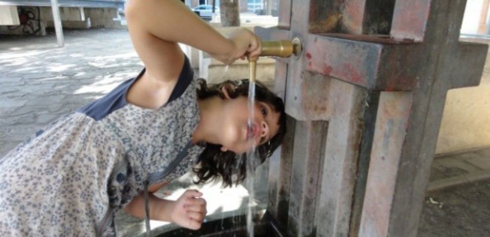 Una nena beu aigua d'una font a Manresa