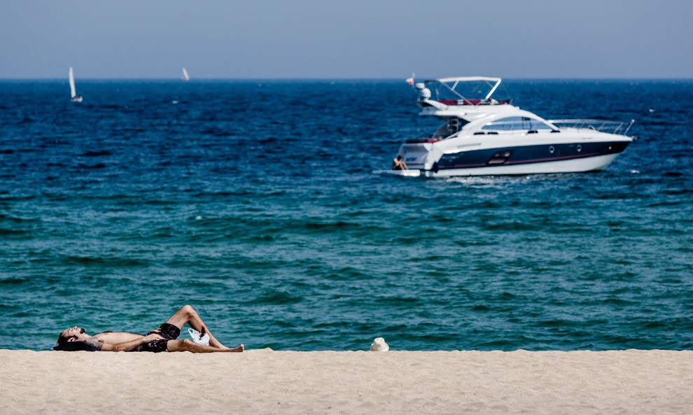 Un home prenent el sol a la platja de Badalona.