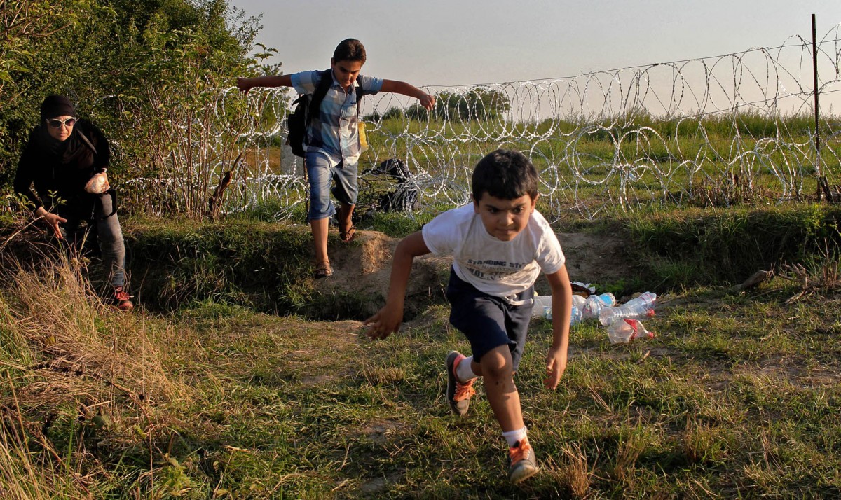 Una família de refugiats saltant la valla de la frontera d'Hongria