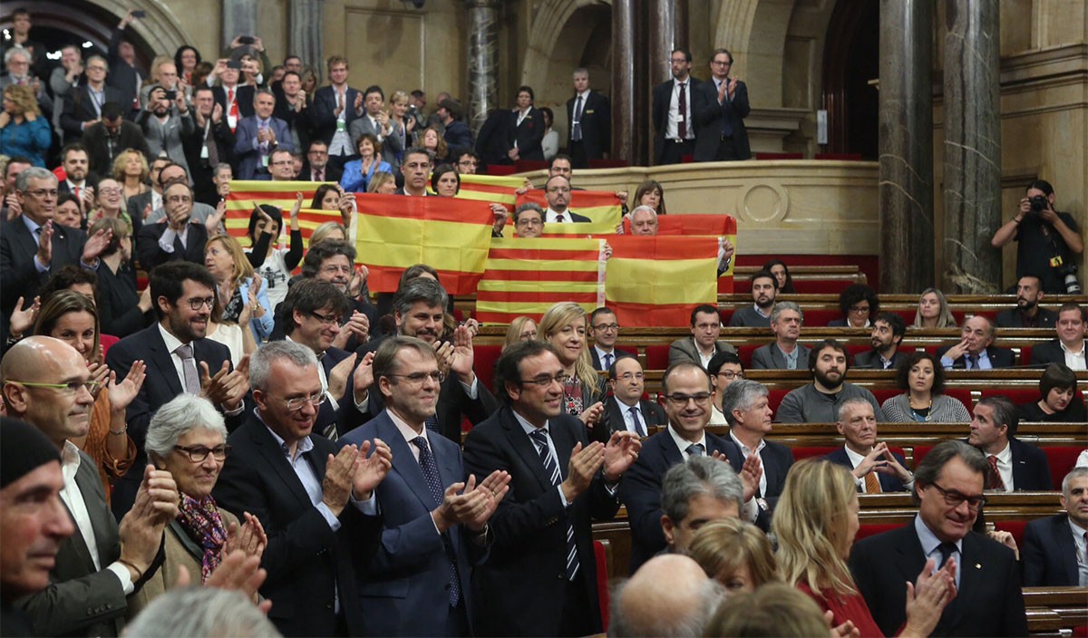 Els diputats independentistes aplaudeixen mentre els del PP despleguen banderes espanyoles