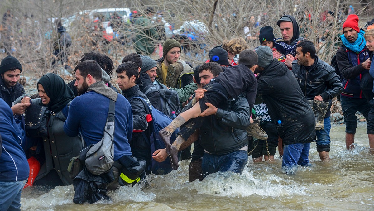 Refugiats creuant un riu entre Grècia i Macedònia