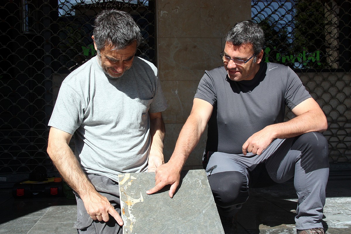 Els geòlegs Roger Mata i Jordi Ferrer, amb el fòssil de la vaca marina incrustat a les llambordes del paviment