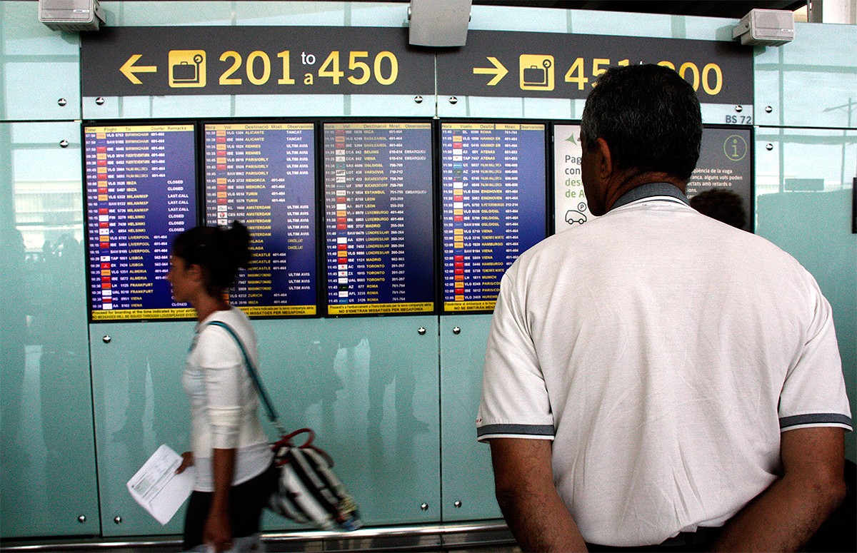 Un passatger observant un panell de vols a l'aeroport del Prat.