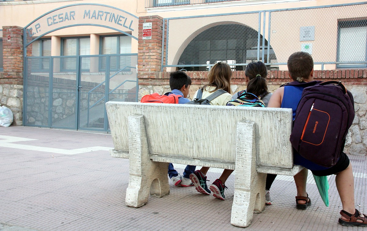Quatre nois esperen asseguts a un banc a les portes de l'escola César Martinell del Pinell de Brai.