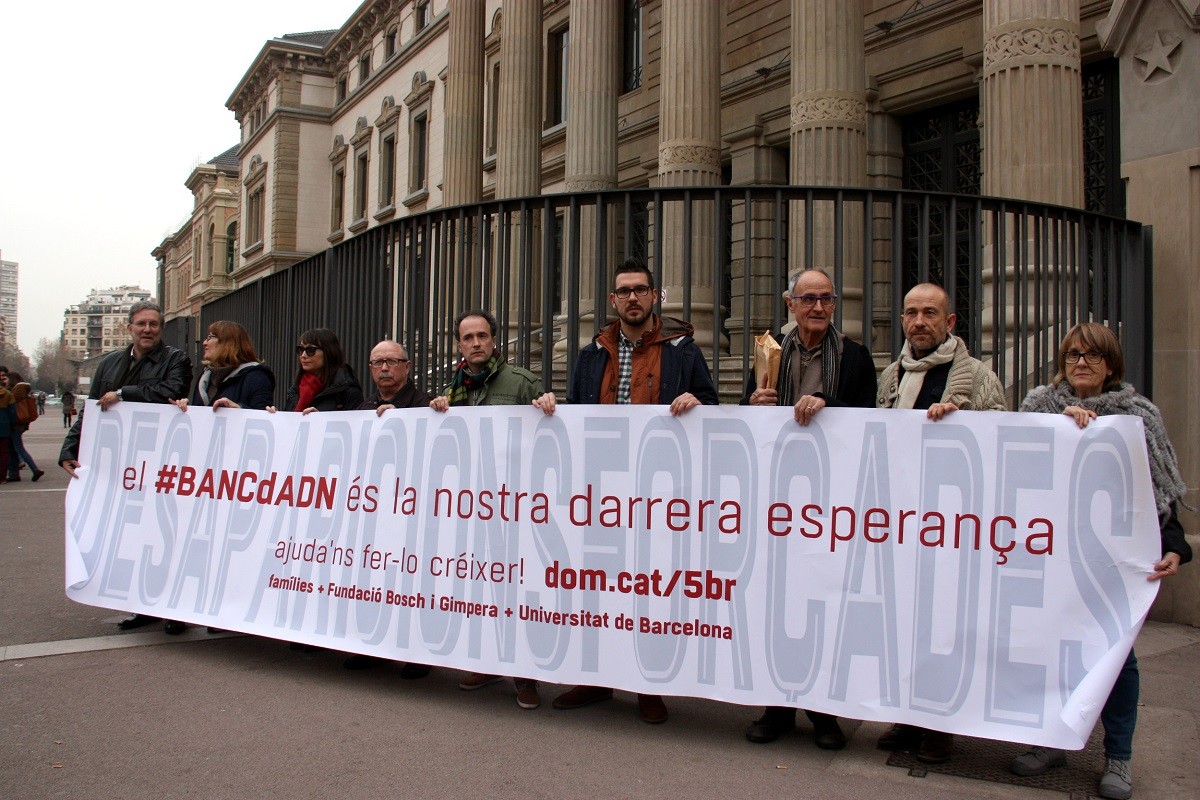 Representants del requeriment judicial pel creuament de dades del Banc d'ADN, davant la Facultat de Medicina de la UB amb una pancarta amb el lema.