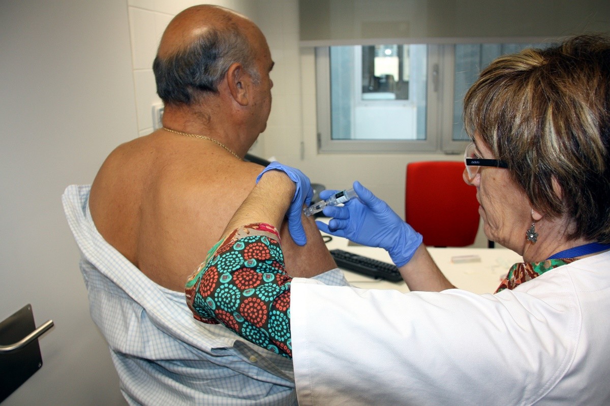 Una infermera posa la vacuna de la grip a un pacient