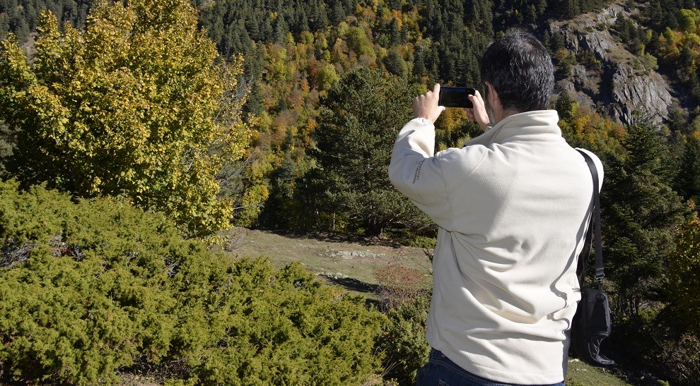 Una persona fa una foto amb el seu mòbil a un paisatge de tardor