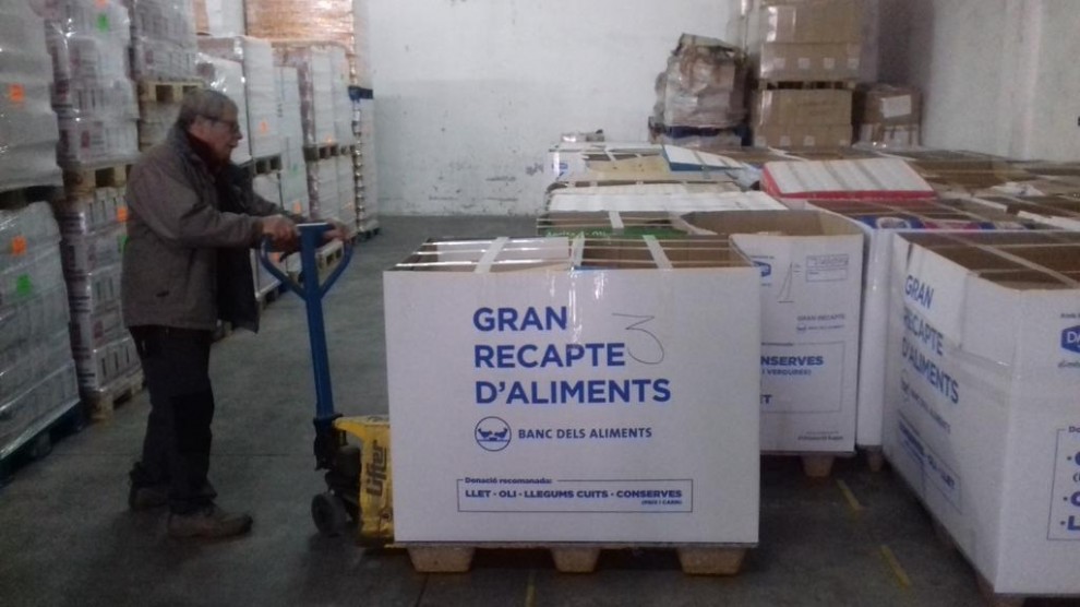 Un voluntari de la Fundació El Xiprer classifica una de les caixes plenes d'aliments