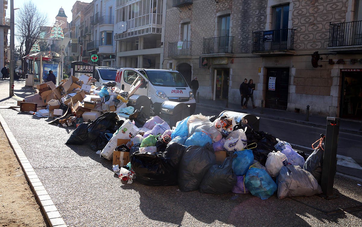 Imatge d'un carrer de Figueres ple de brossa amb els contenidors plens aquest divendres