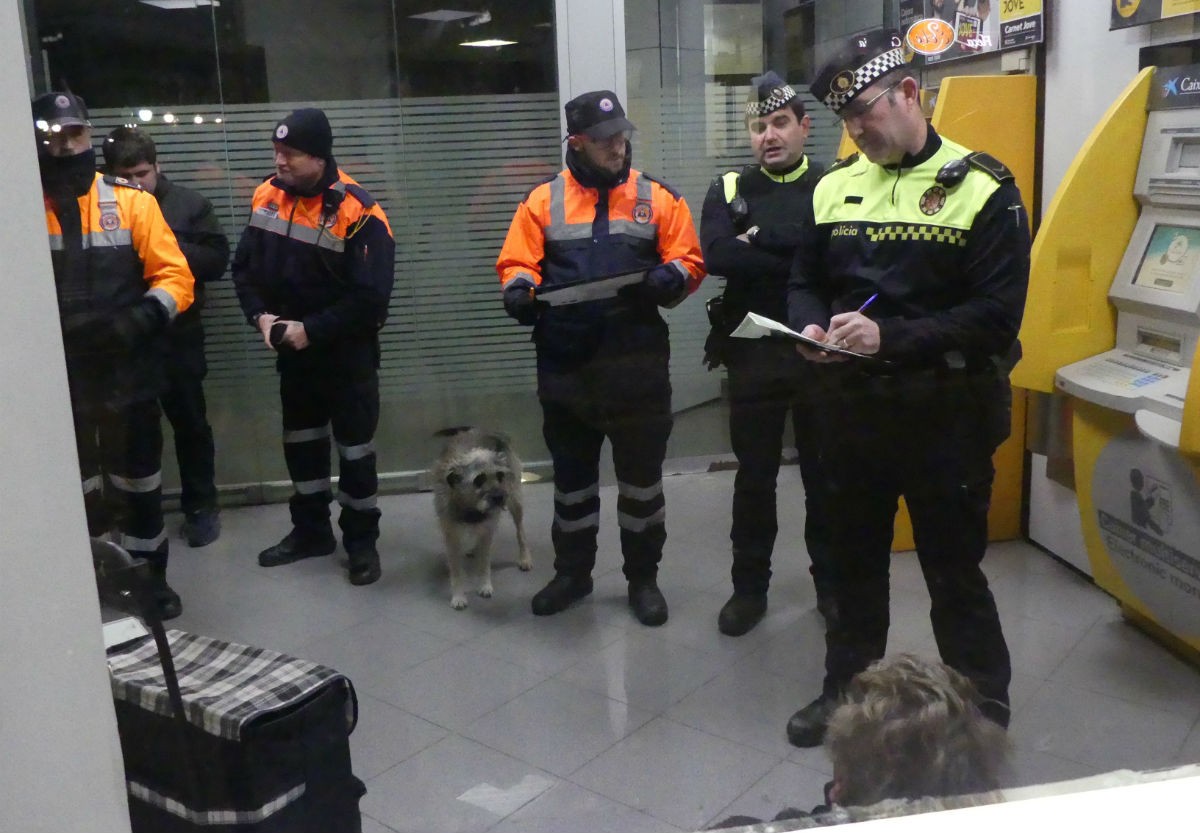 Agents de la Guàrdia Urbana i membres de Protecció Civil parlant amb una persona que dormia en un caixer  a Tarragona 