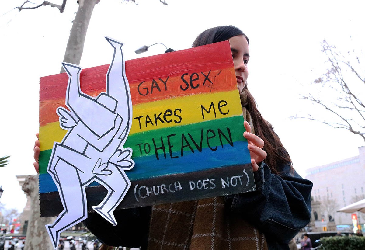 Una noia amb un cartell on es pot llegir en anglès  «El sexe gay em porta al paradís, no l'Església»