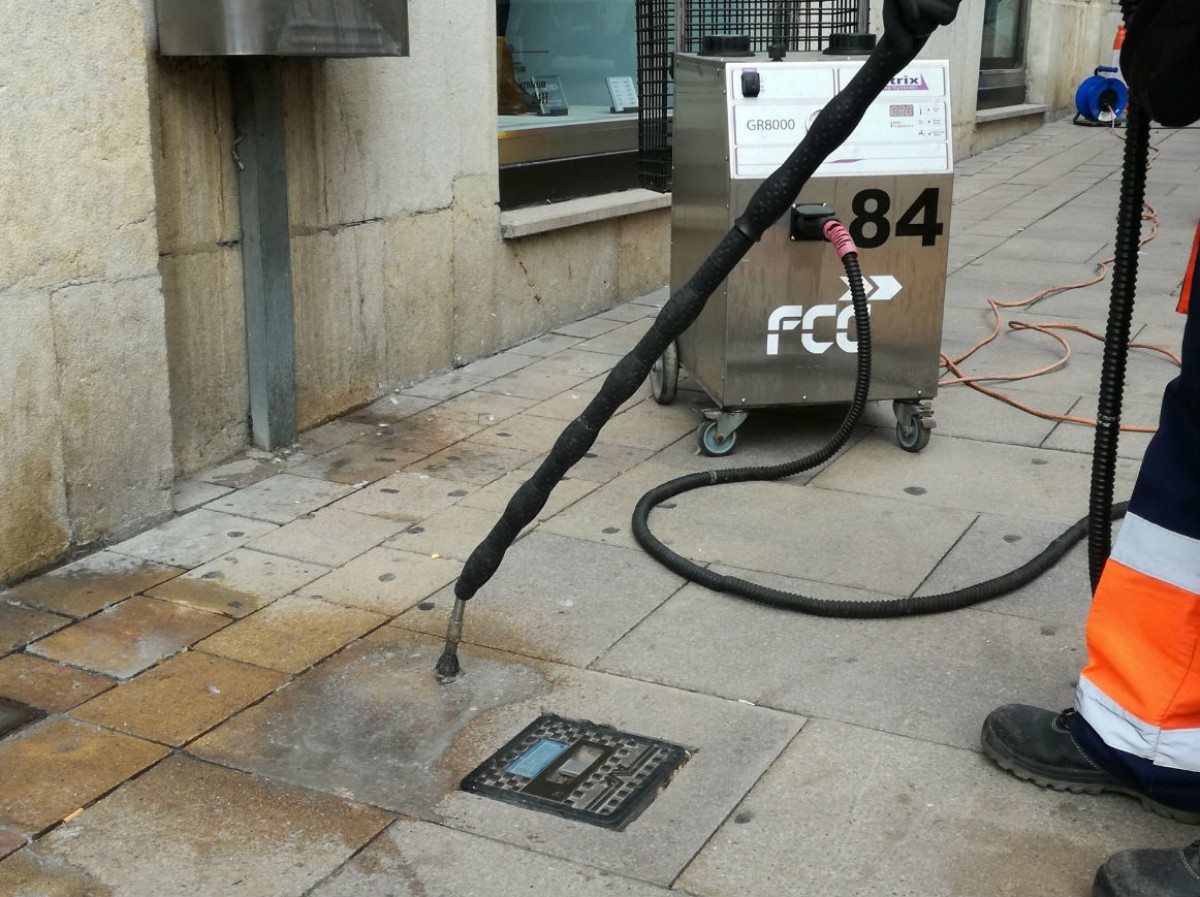 Un operari netejant xiclets enganxats al carrer