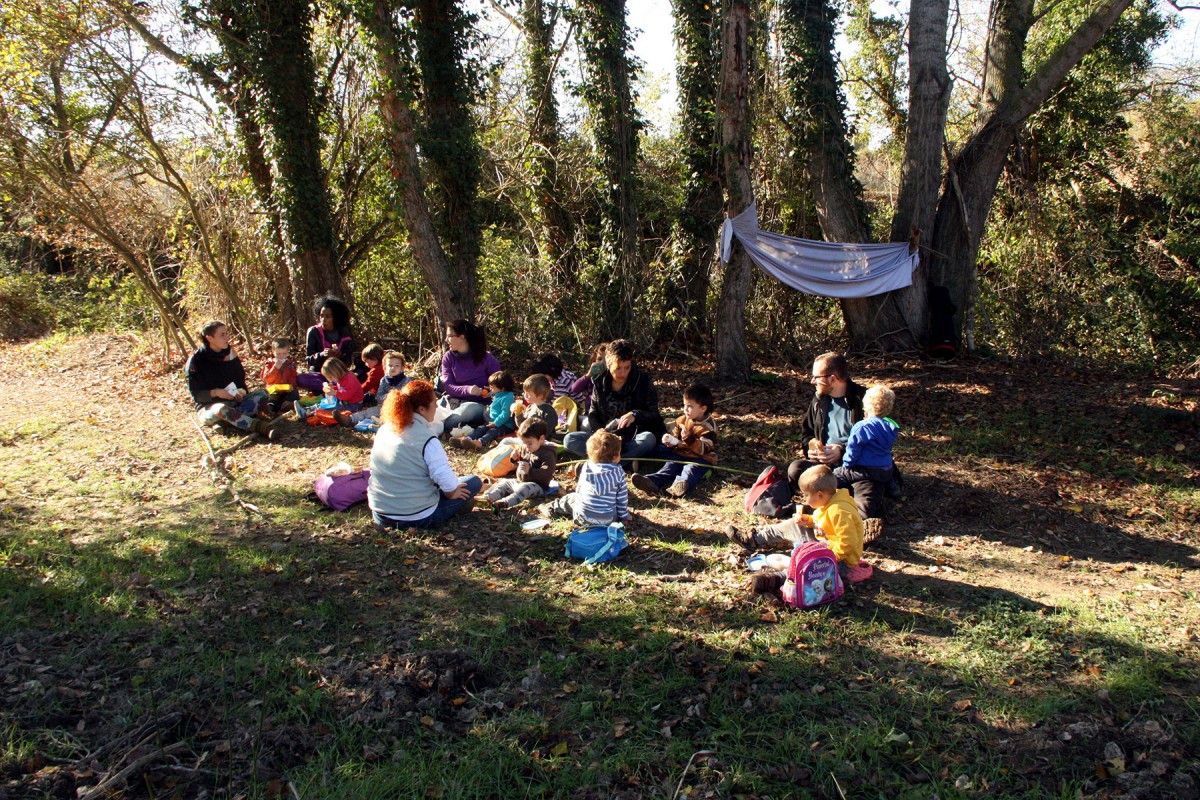 La quinzena d'alumnes de Rubió asseguts al bosc a l'hora d'esmorzar