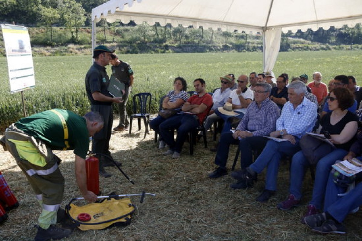 Els Agents Rurals expliquen a un grup de pagesos com funcionen els extintors que han d'utilitzar durant la campanya de la sega