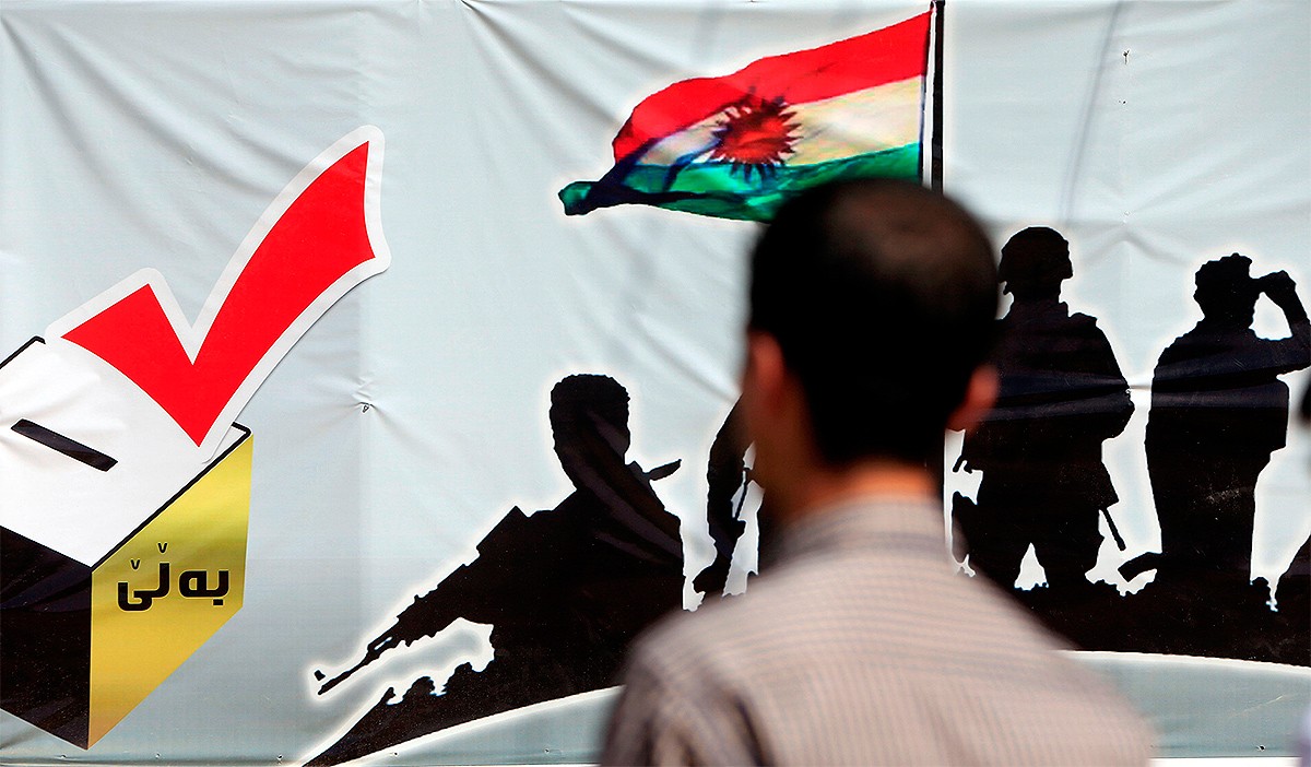 Un home mira un cartell del referèndum al Kurdistan, aquest dilluns
