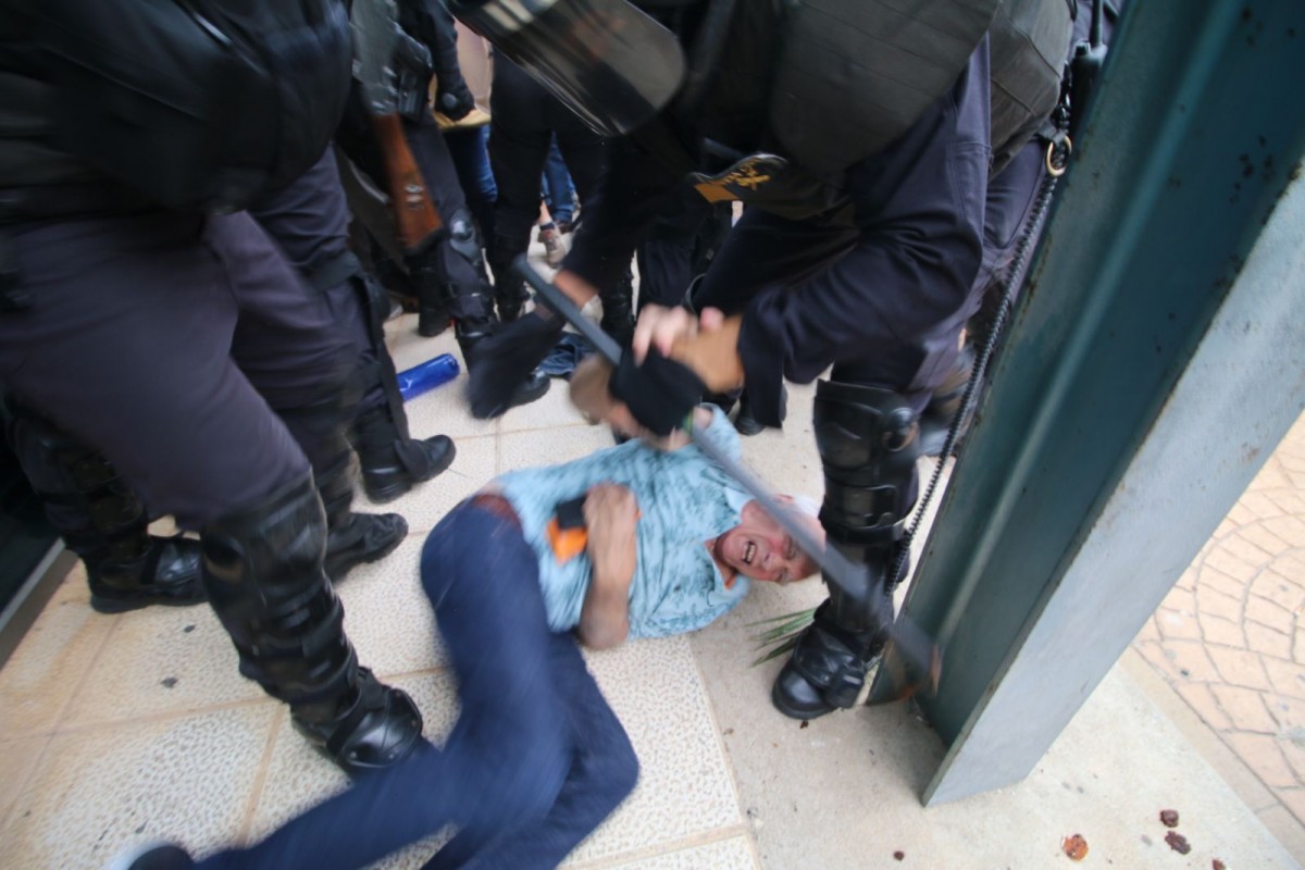 Un home, estirat a terra mentre els policies l'agredeixen l'1-O
