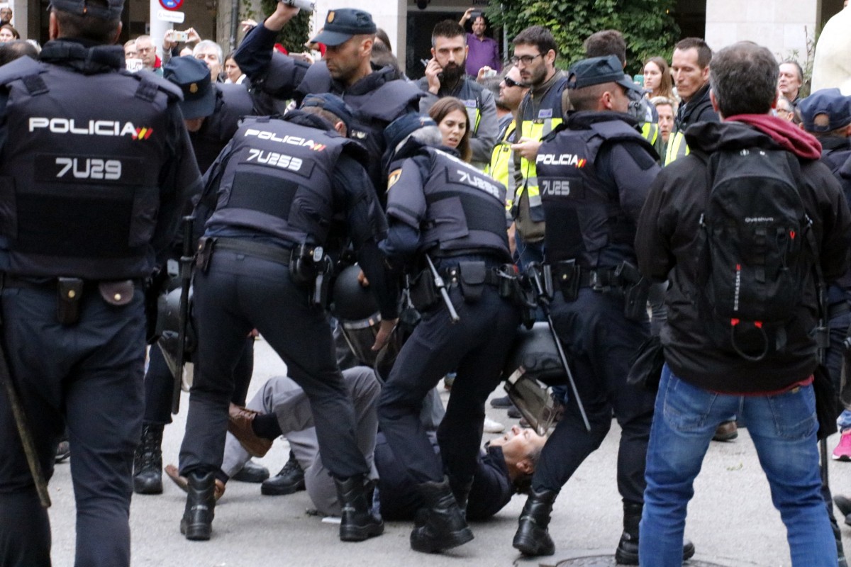 Un votant és reprimit a terra per la policia espanyola en un centre electoral a Girona.