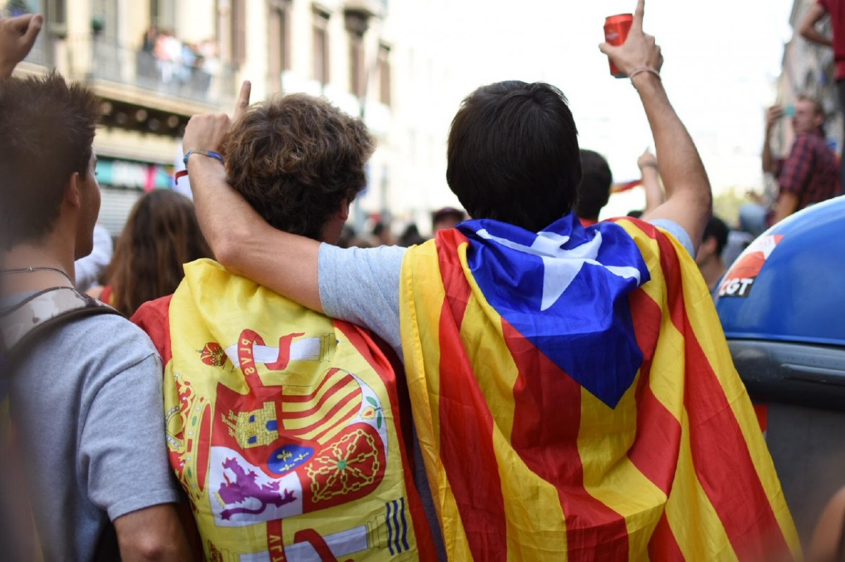 Dos joves amb una bandera espanyola i una estelada protesten contra la violència policial, en una manifestació.