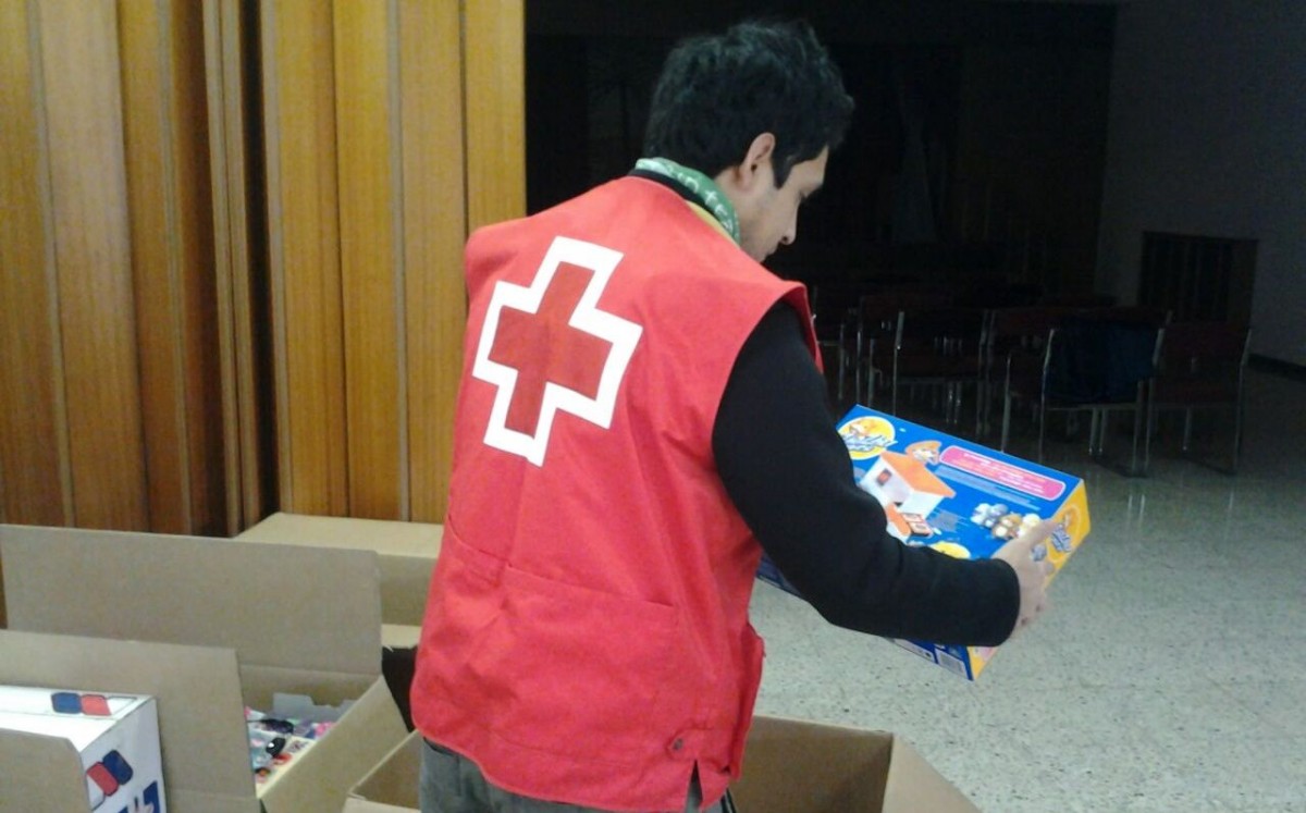 Un voluntari de Creu Roja classificant els regals per la Campanya de Joguines