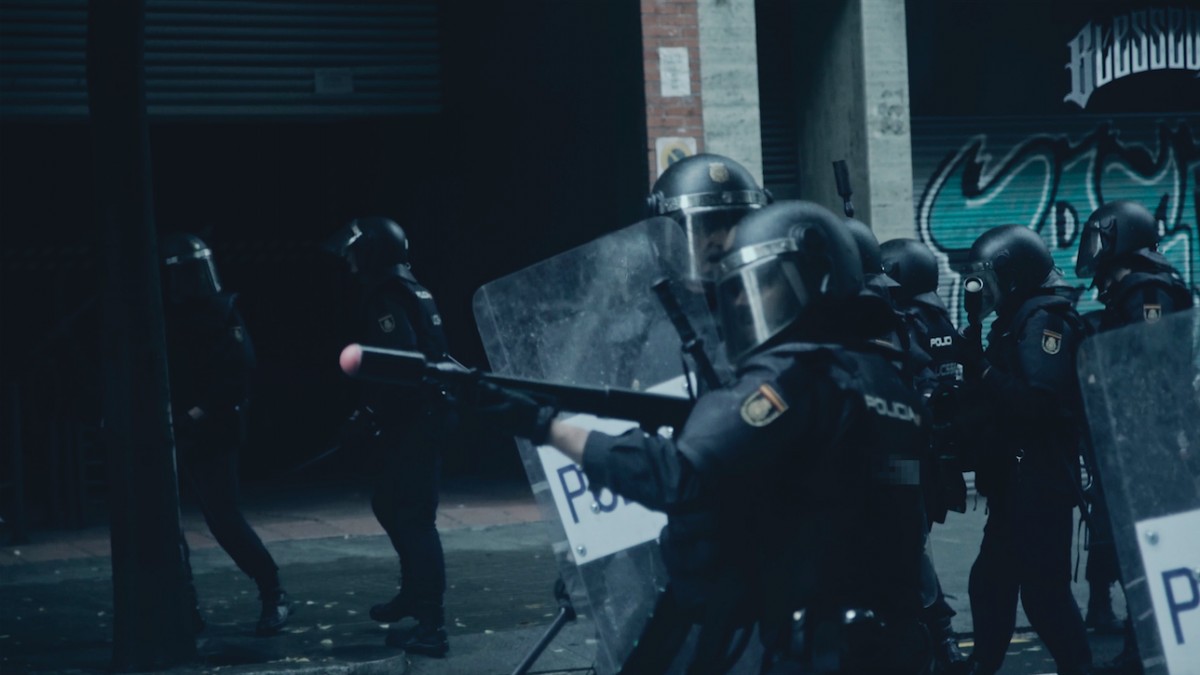 Un agent de la policia espanyola disparant una escopeta durant l'1-O