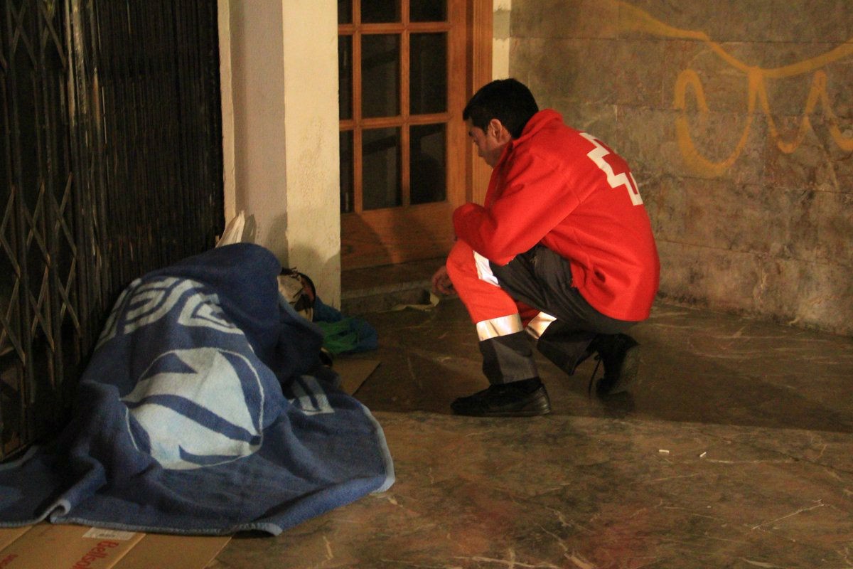Un voluntari de la Creu Roja parlant amb un sensesostre