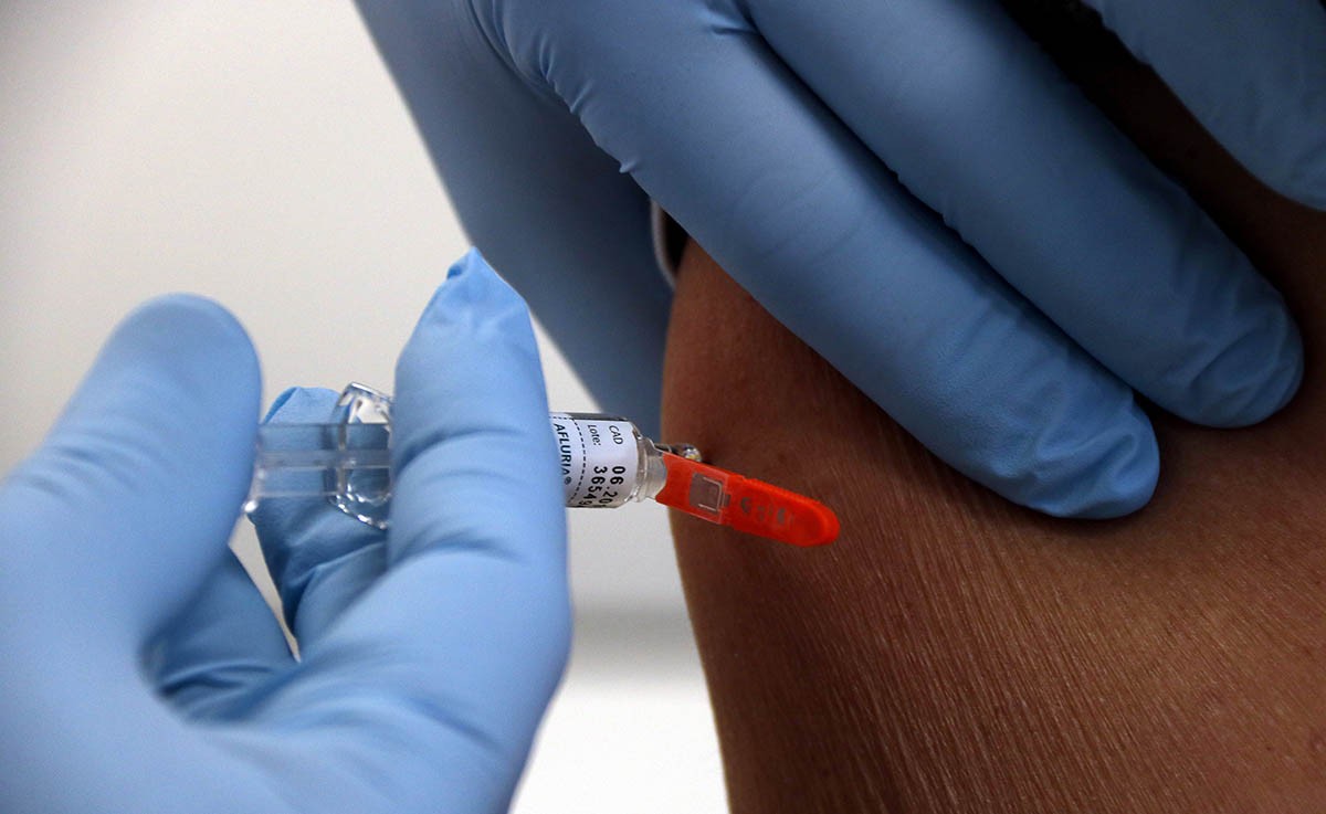 Un professional introdueix el vaccí de la grip en un pacient.