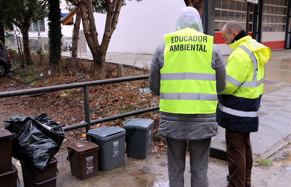 Un educador ambiental revisant els cubells del servei de recollida selectiva de residus