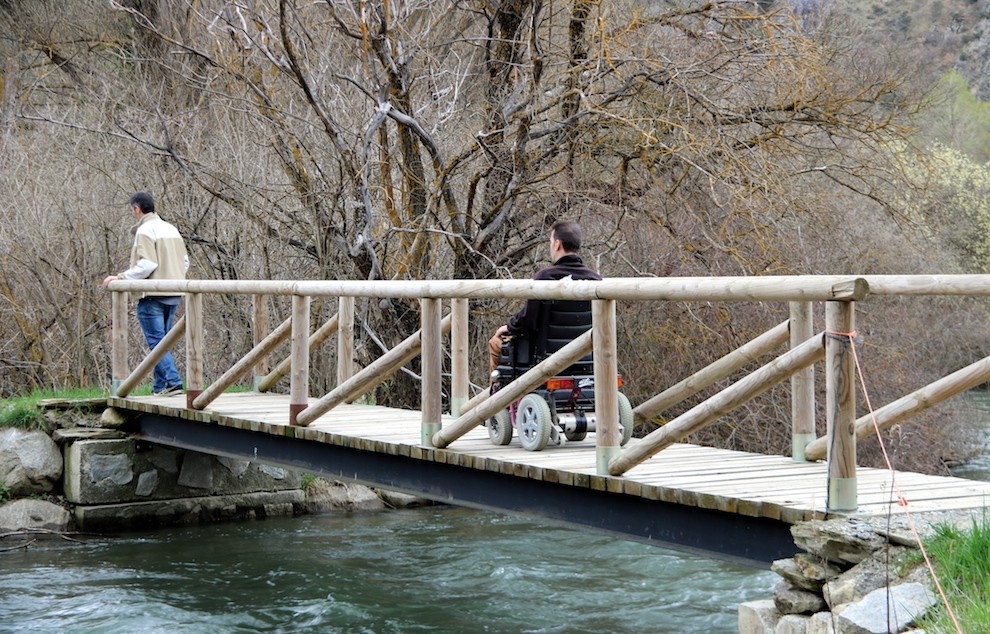 Dos usuaris passen per un pont sobre la Noguera Pallaresa.