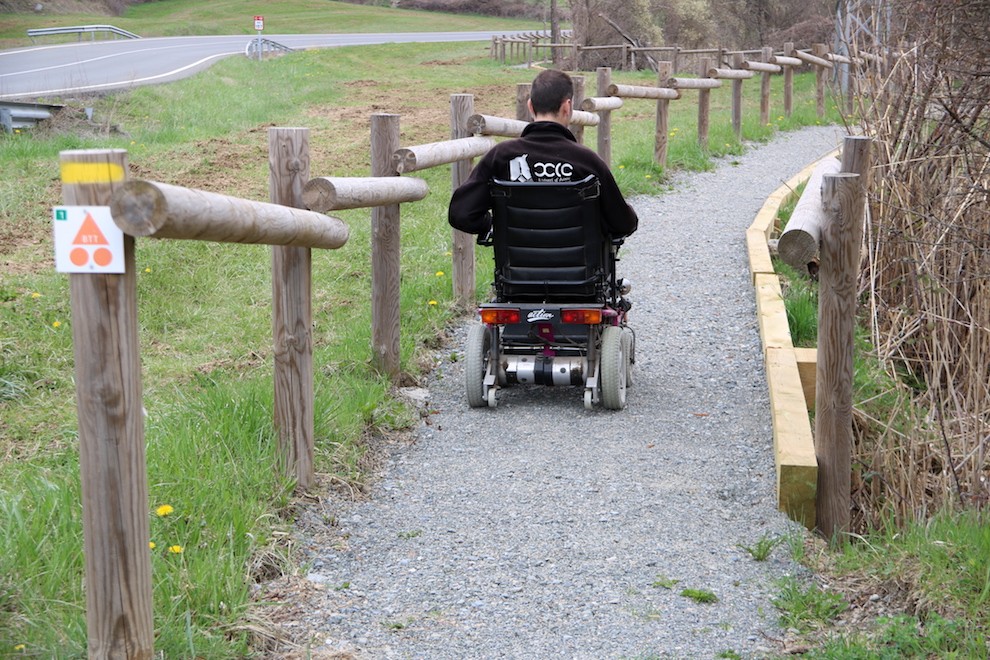 Un home en cadira de rodes en un itinerari de turisme rural.