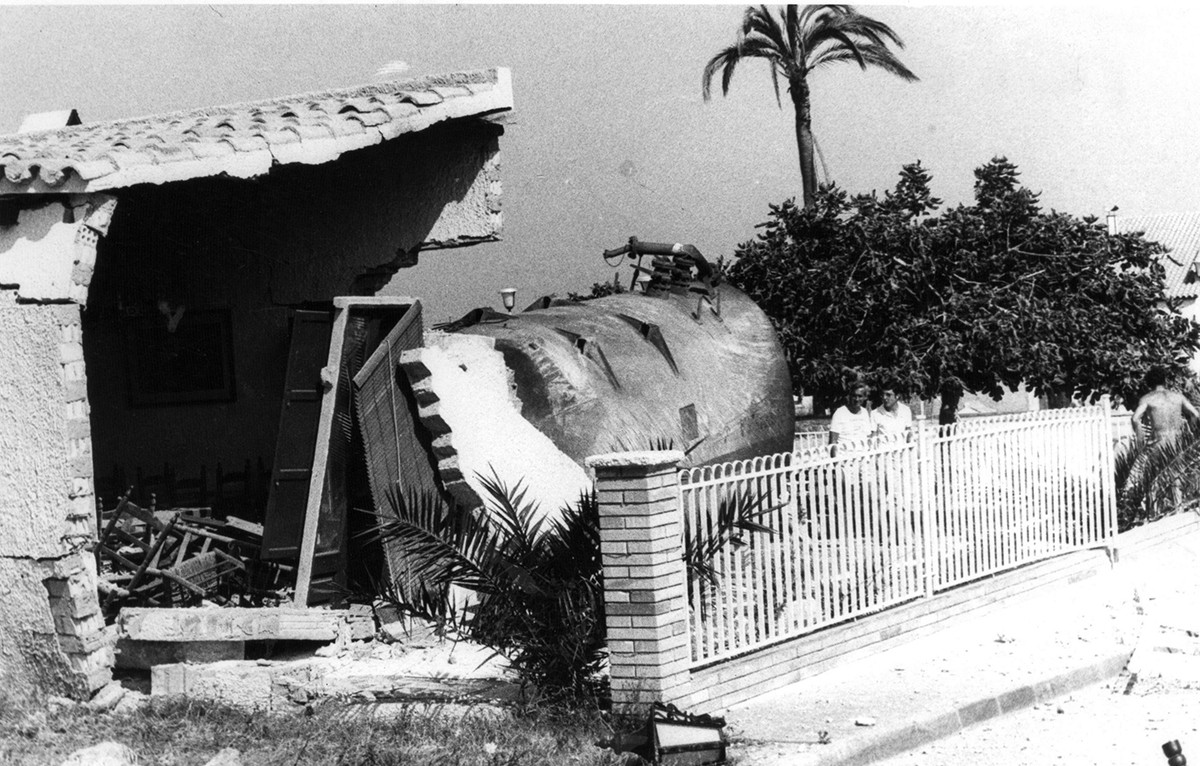 Cisterna al costat d'una casa destruïda.