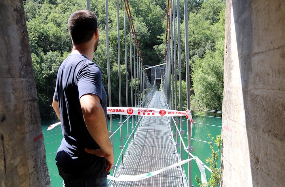 Un home mira el pont penjat amb l’accés a Mont-rebei tallat