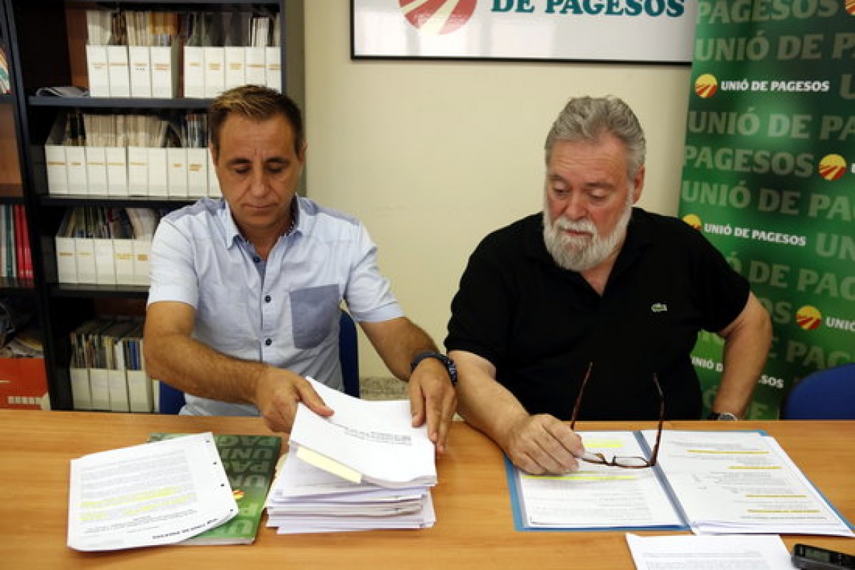 Els integrants d'Unió de Pagesos Josep Guitart i Joan Casajoana consulten documentació relacionada amb les immatriculacions del bisbat de Vic i de Solsona.