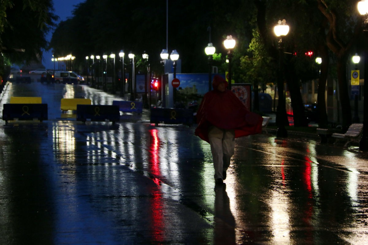 Un home amb un impermeable vermell a la Rambla de Tarragona sota la pluja intensa