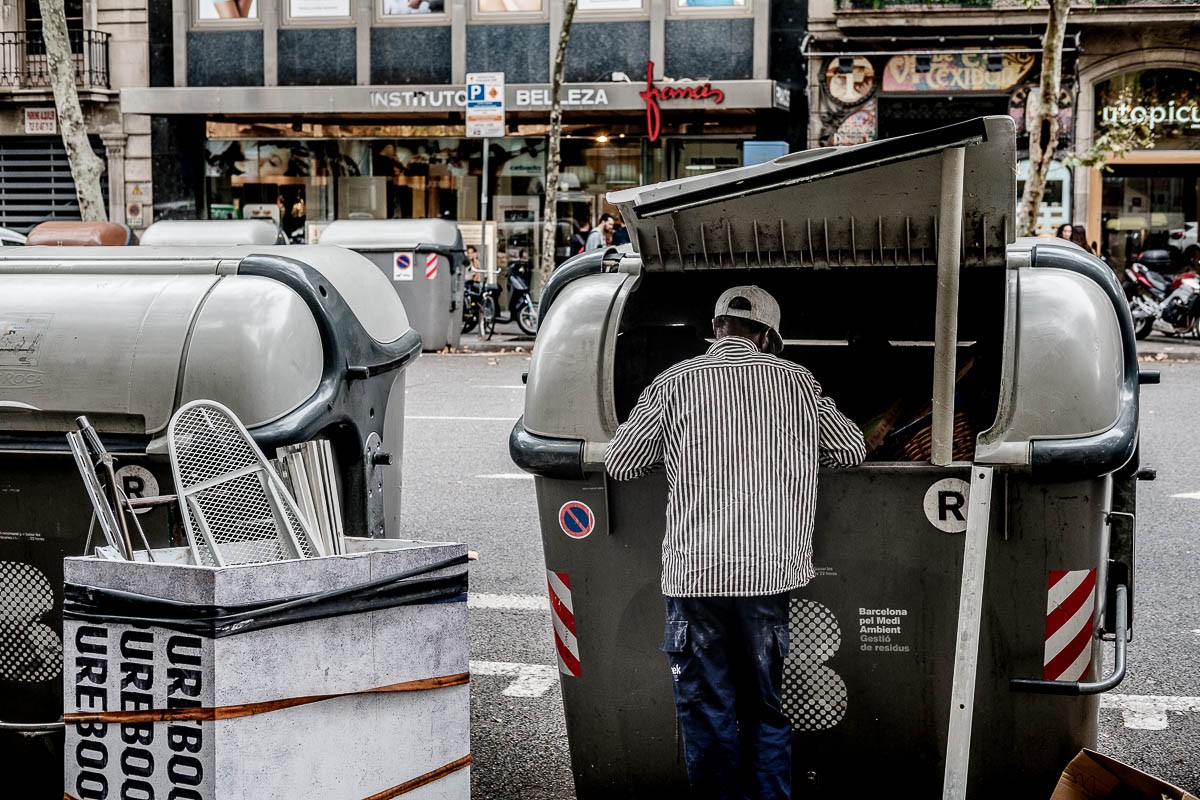 Un home busca ferralla en un contenidor del centre de Barcelona