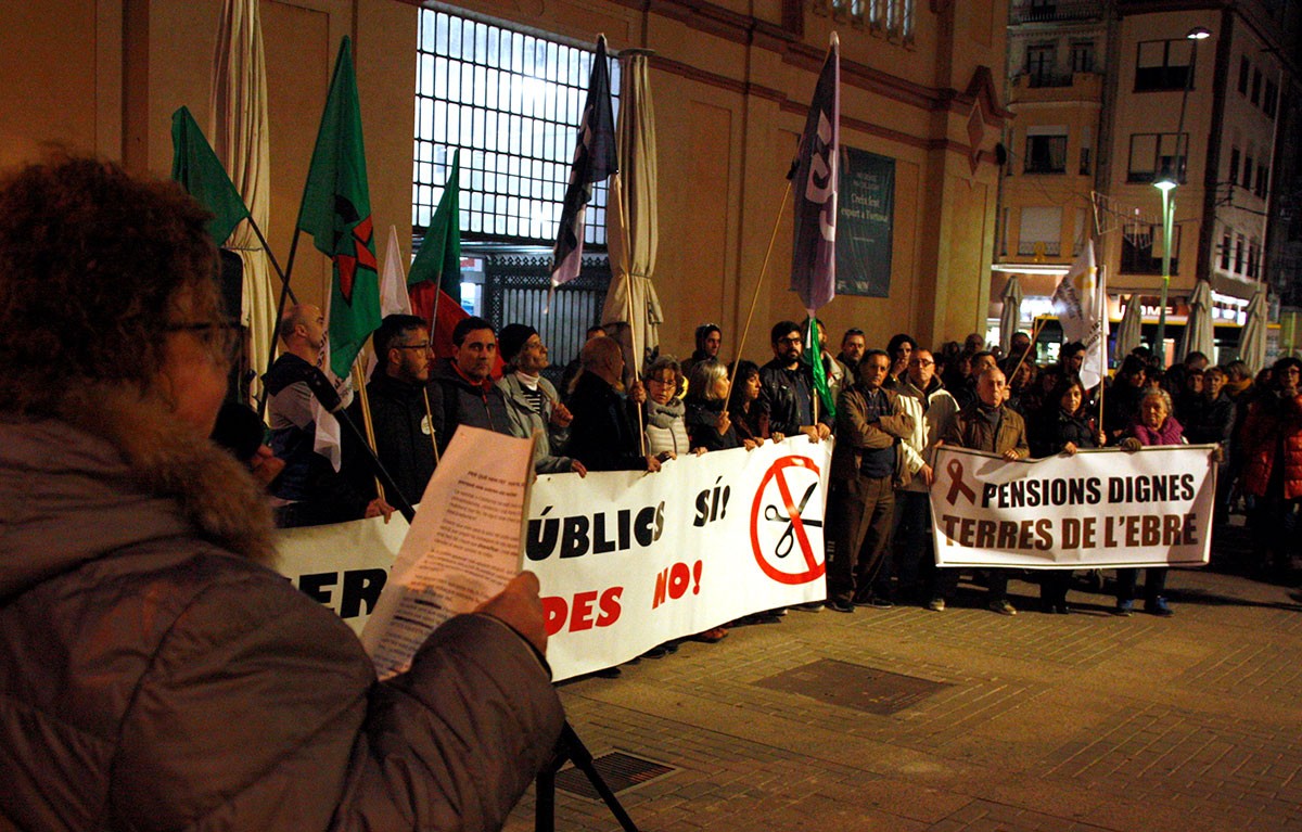 La representant de CATAC, Cinta Sarroca, llegint el manifest davant d'alguns assistents amb pancartes, a la concentació de Tortosa. 