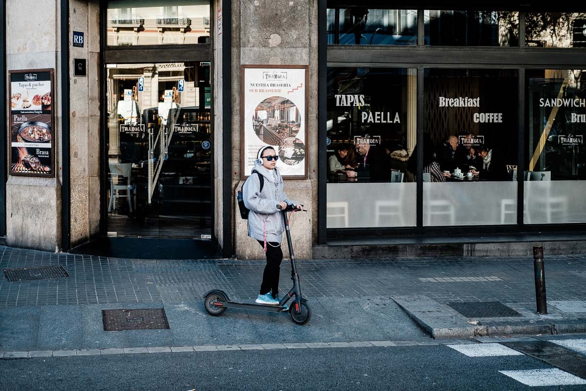 Una noia amb patinet elèctric espera per creuar un pas de vianants del centre de Barcelona