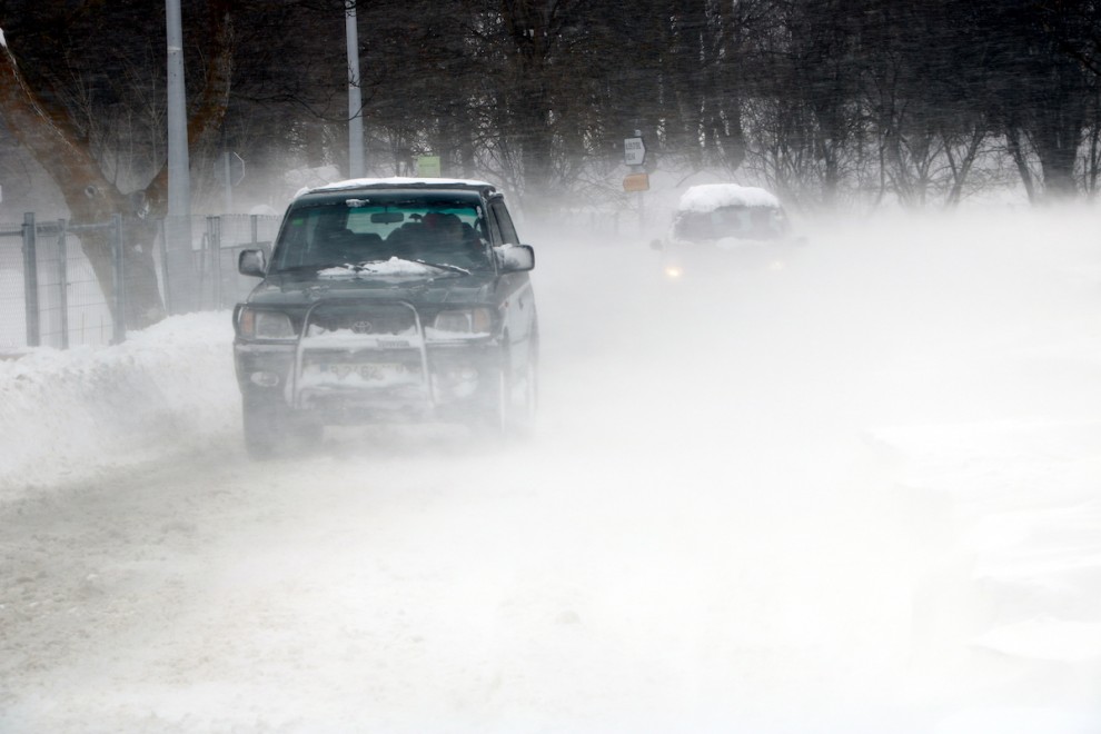 Dos vehicles circulant enmig de la ventisca que aixeca la neu