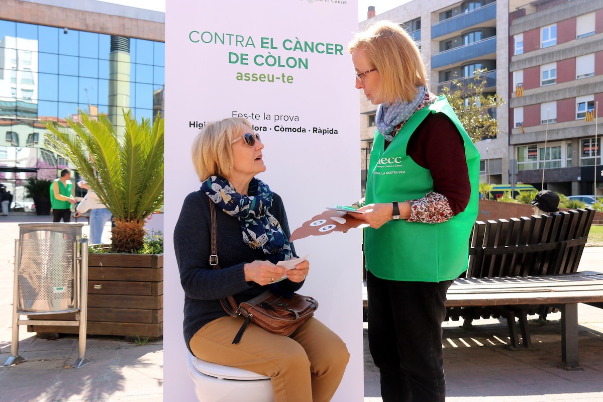 Una voluntària informa una dona sobre el programa de cribatge a Girona.