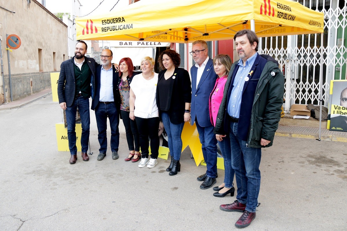 Els candidats d'ERC Miquel Aubà i Norma Pujol, al centre, en una carpa electoral  davant del mercat d'Alcanar.