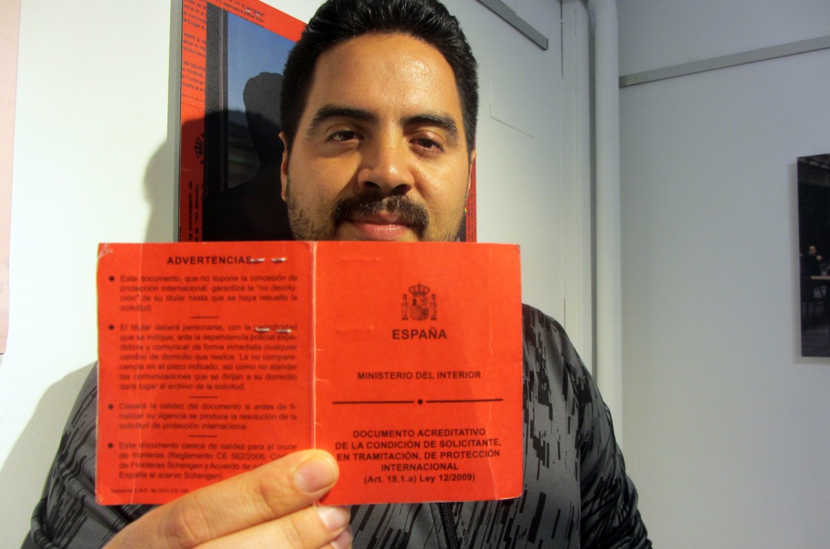 Mostra el seu carnet vermell que acredita la la sol·licitud d'asil