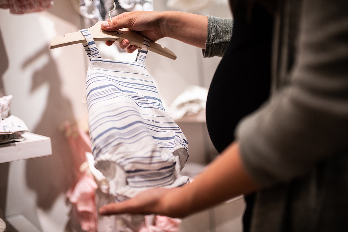 Una dona embarassada mirant roba de nadó