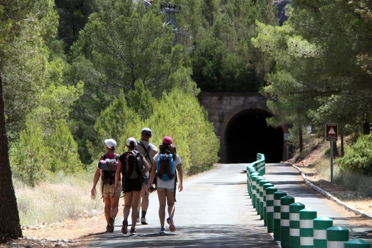 Una família de turistes amb motxilles caminant per la via verda, a punt d'endinsar-se a un túnel, a Prat de Comte, a la Terra Alta.