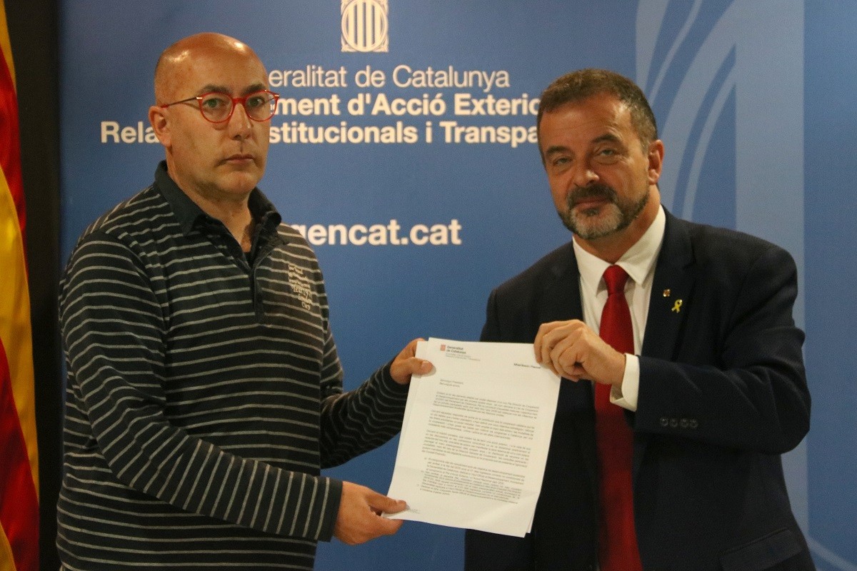 El president del Consell Català de Cooperació al Desenvolupament, Lluís Puigdemont, rep de la mà del conseller Bosch, el compromís de la Generalitat amb l'objectiu de destinar el 0,7% a cooperació