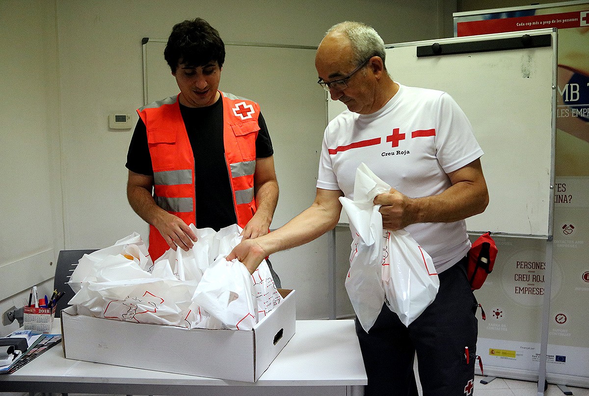 Dos voluntaris de la Creu Roja de Girona preparant els paquets