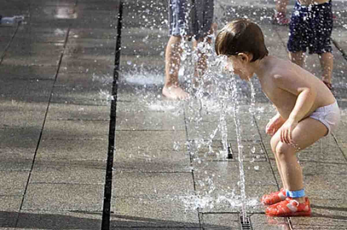 Un nen es refresca amb l'aigua 