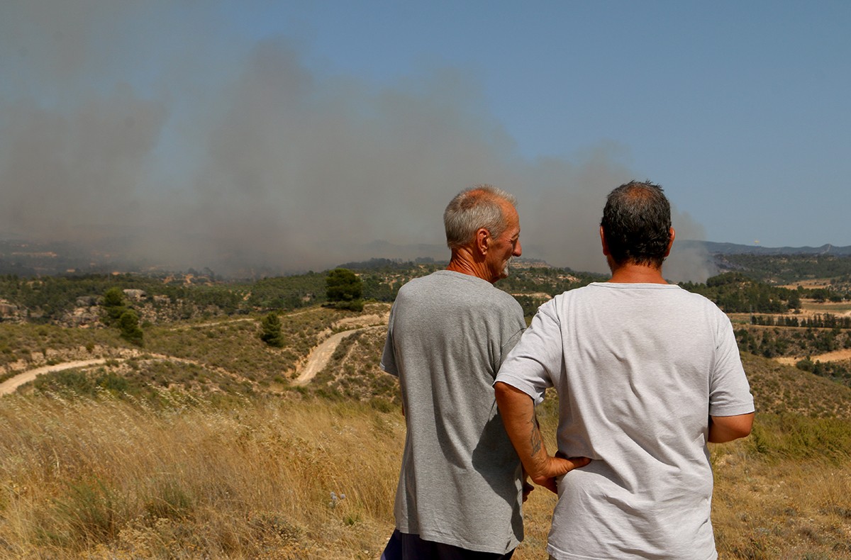 Dos homes observen l'avanç de les flames a l'horitzó