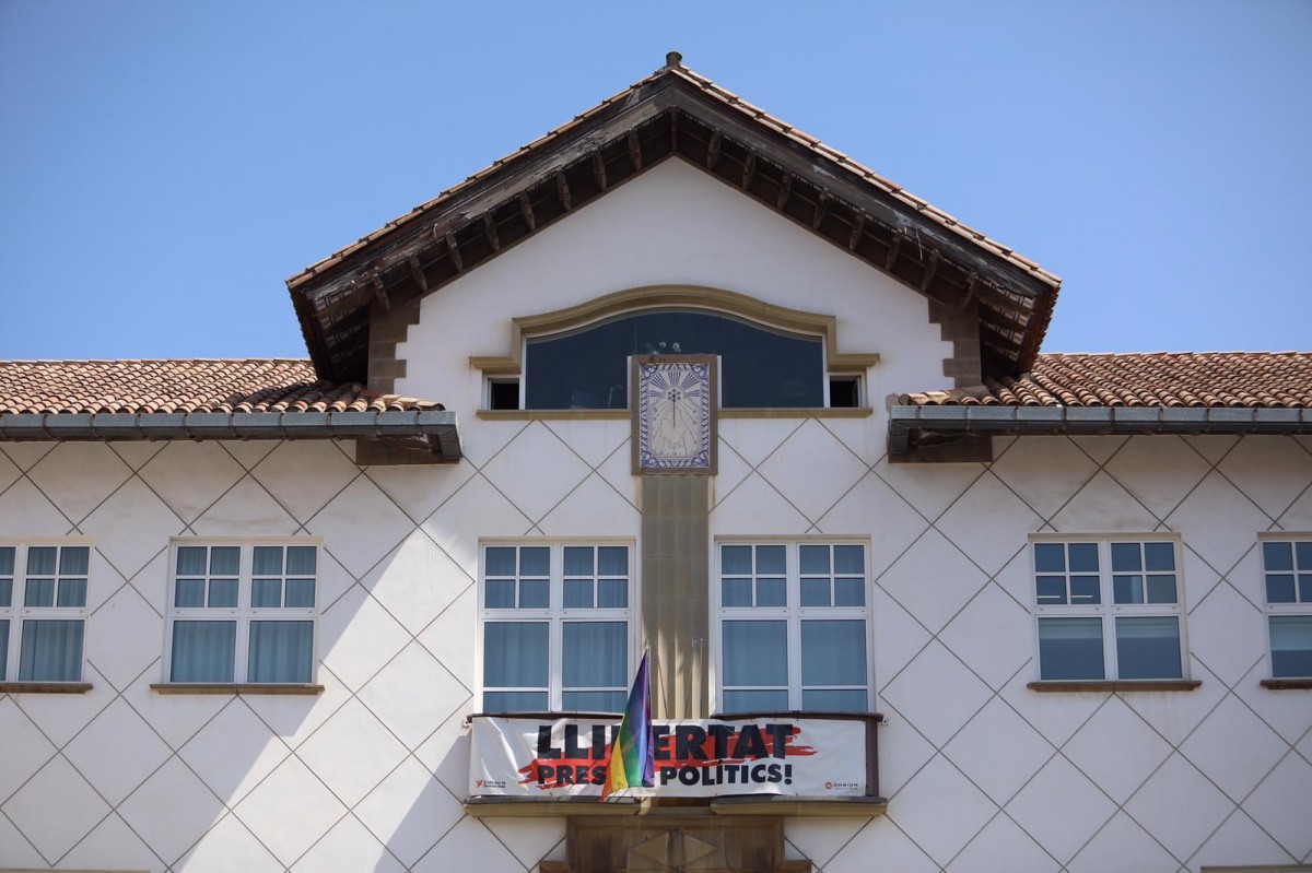 Façana de l'Ajuntament d'Olot amb una pancarta reivindicativa i la bandera LGTBI.