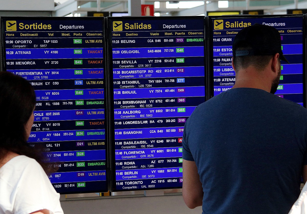 Una pantalla informativa amb les sortides dels vols, alguns d'ells amb retard, a la T-1 de l'aeroport del Prat.