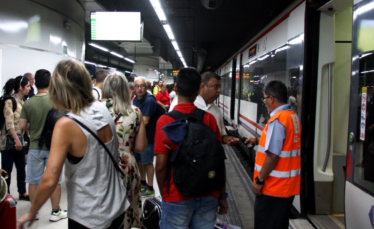 Usuaris de Renfe a l'andana pujant al tren a l'Estació de Sants